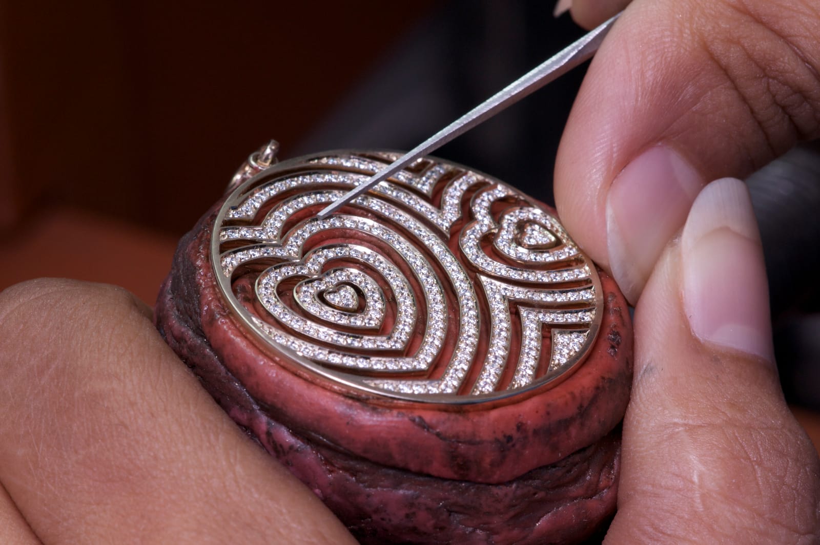 A setter seats diamonds into a pavé heart pendant held in setter's wax at the Eclats bench.