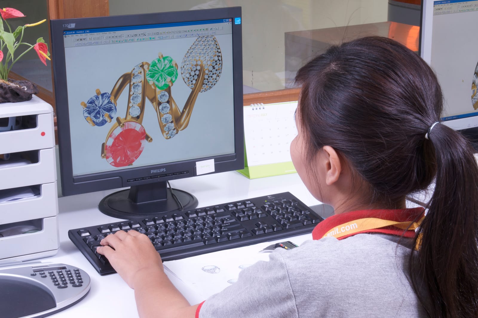 A designer builds a ring in CAD on screen at the design bench.