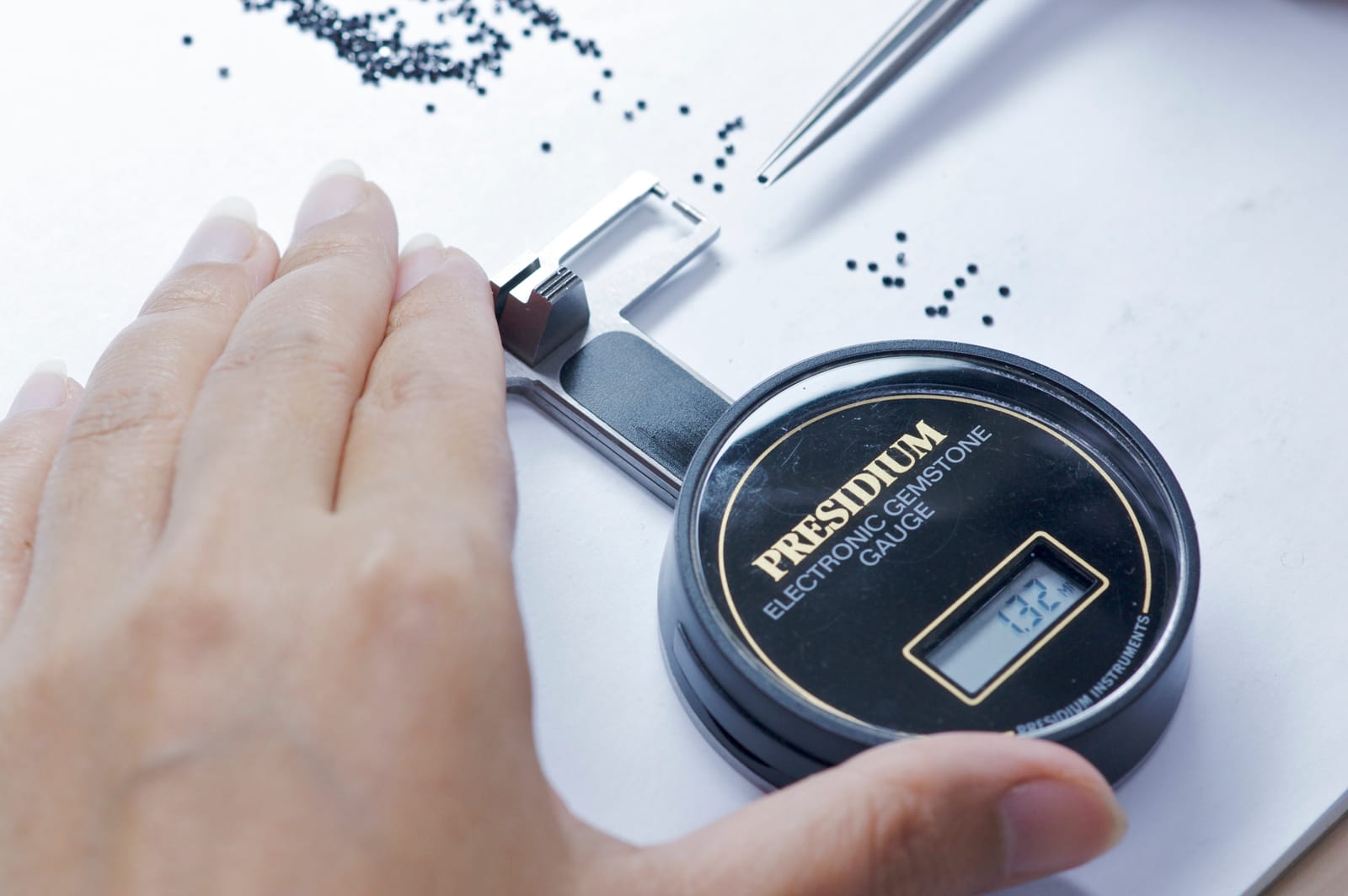 A loose stone is measured on an electronic gemstone gauge.