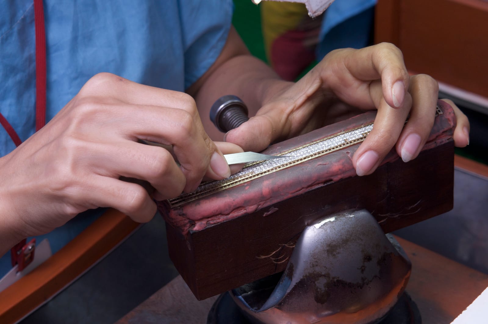 A row of stones is set into a strip held on a shellac block.